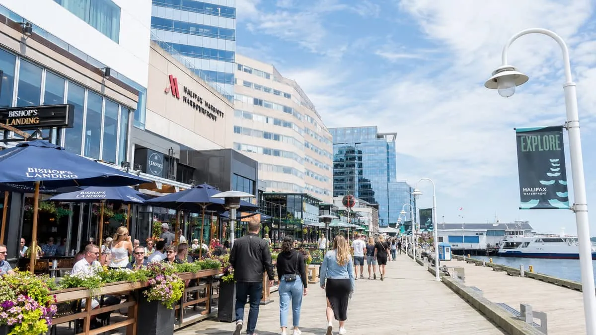 Halifax waterfront boardwalk hospitality district showing restaurant patios, hotel facades, and boardwalk foot traffic o
