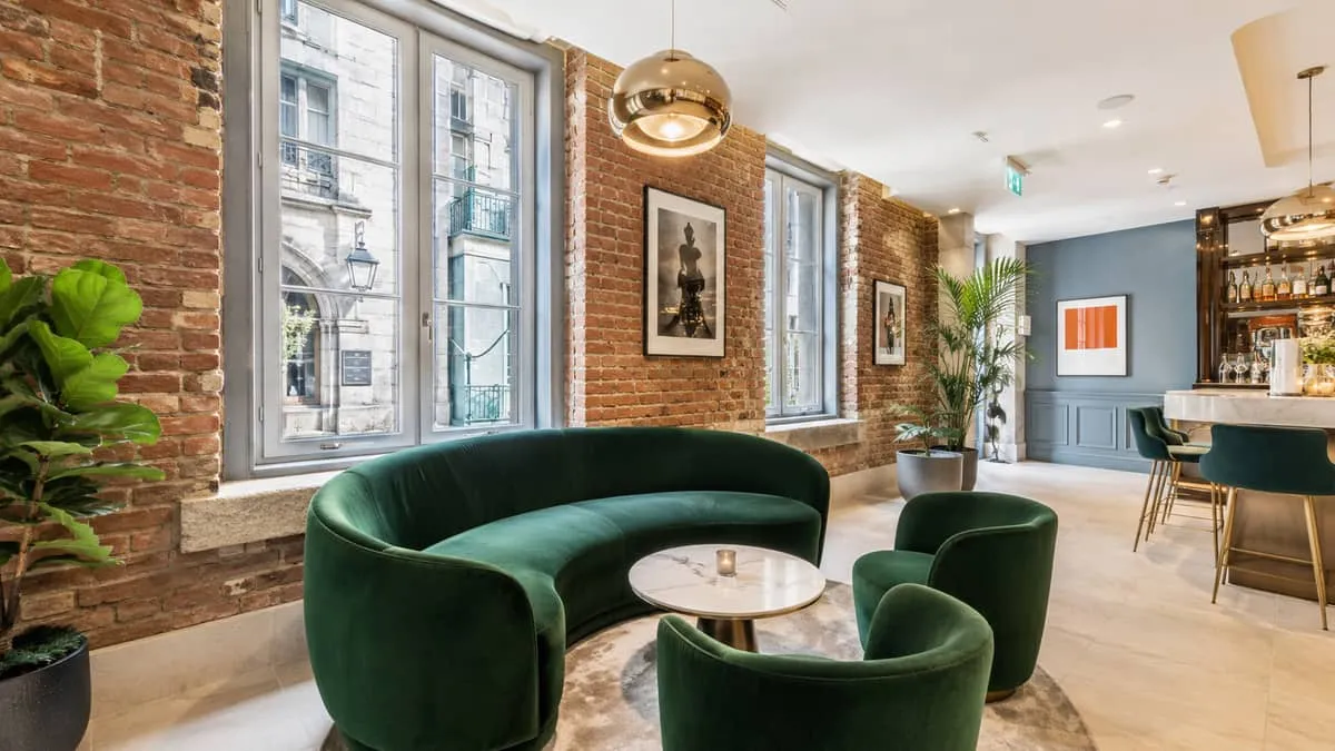 a stylish lounge corner in a Montreal boutique bar showing a curved velvet lounge chair, low cocktail table, and pendant
