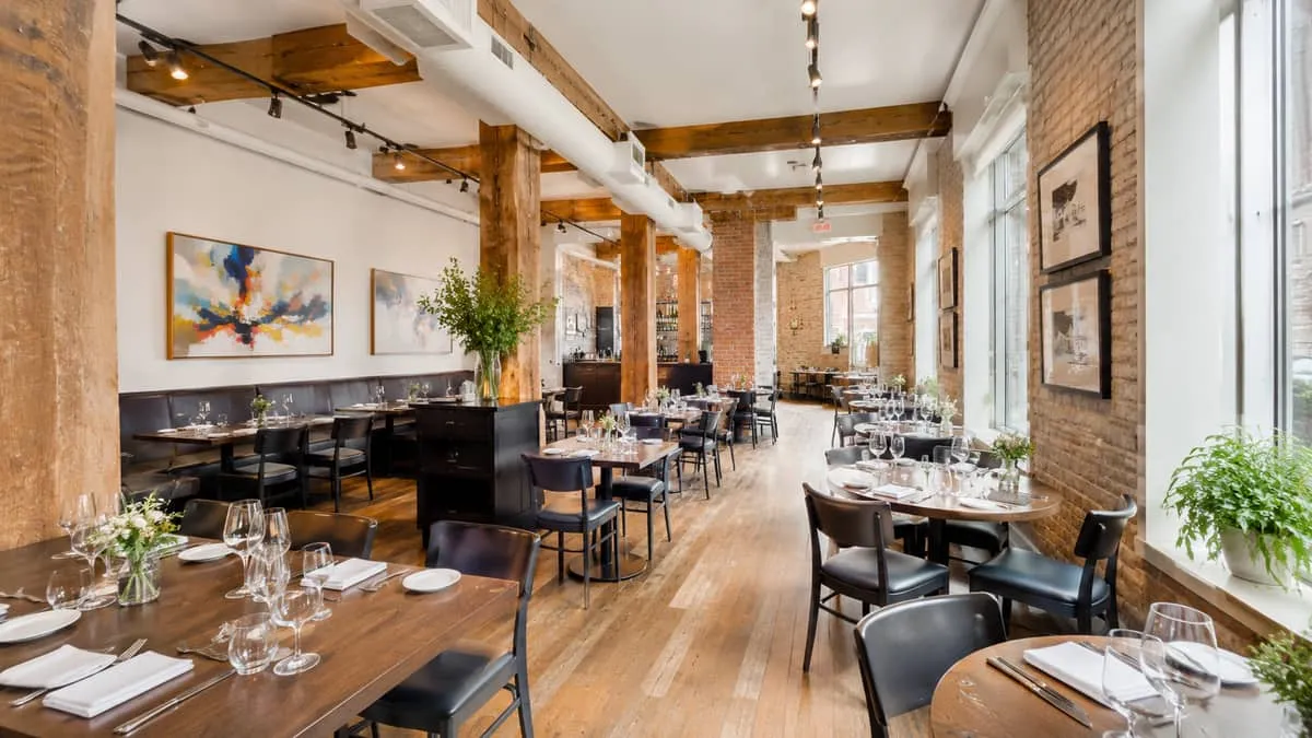 photo of a Montreal restaurant dining room fully set with matching contract-grade chairs and tables, warm lighting, show