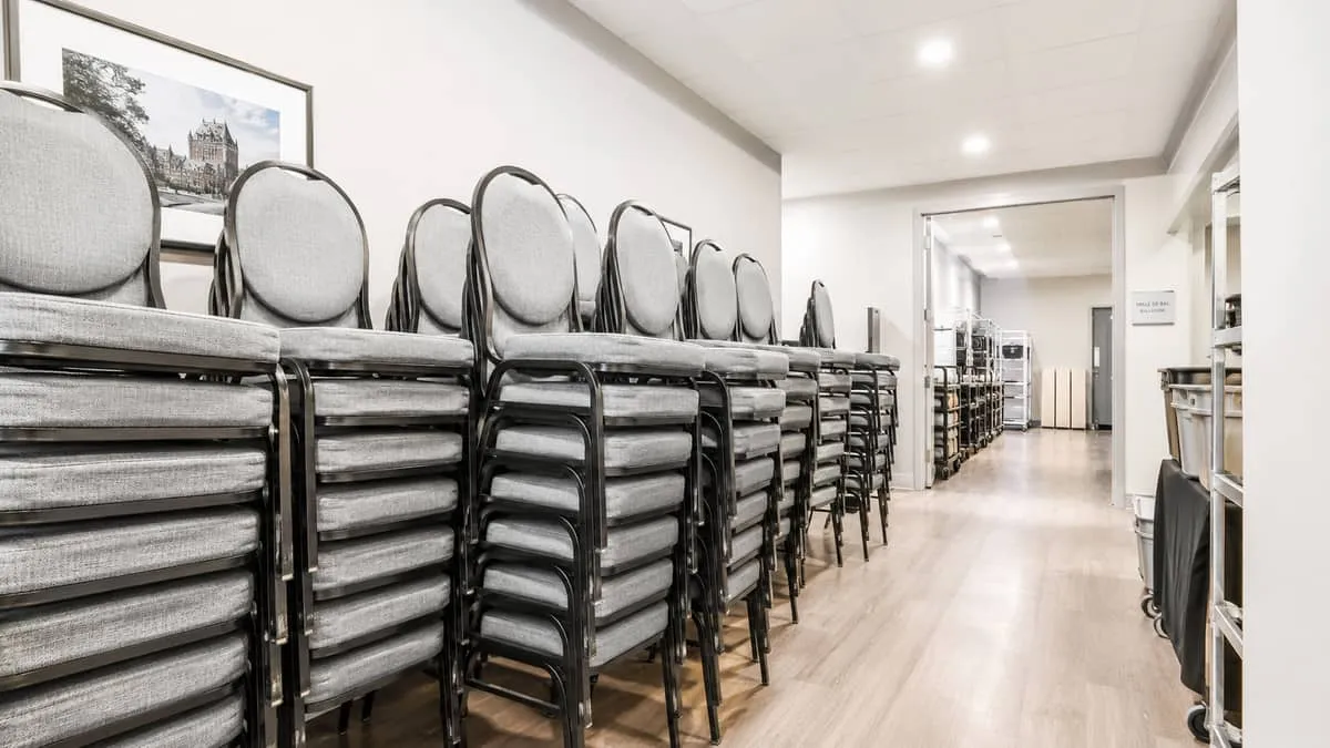 rows of stackable banquet chairs stored neatly in a back-of-house storage area inside a Quebec City hotel or event venue