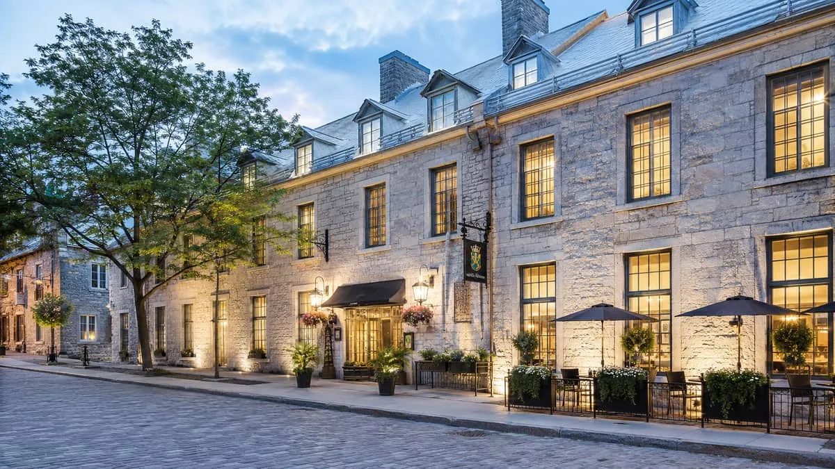 exterior shot of a historic Quebec City event venue or hotel at dusk, with warm interior lighting visible through window