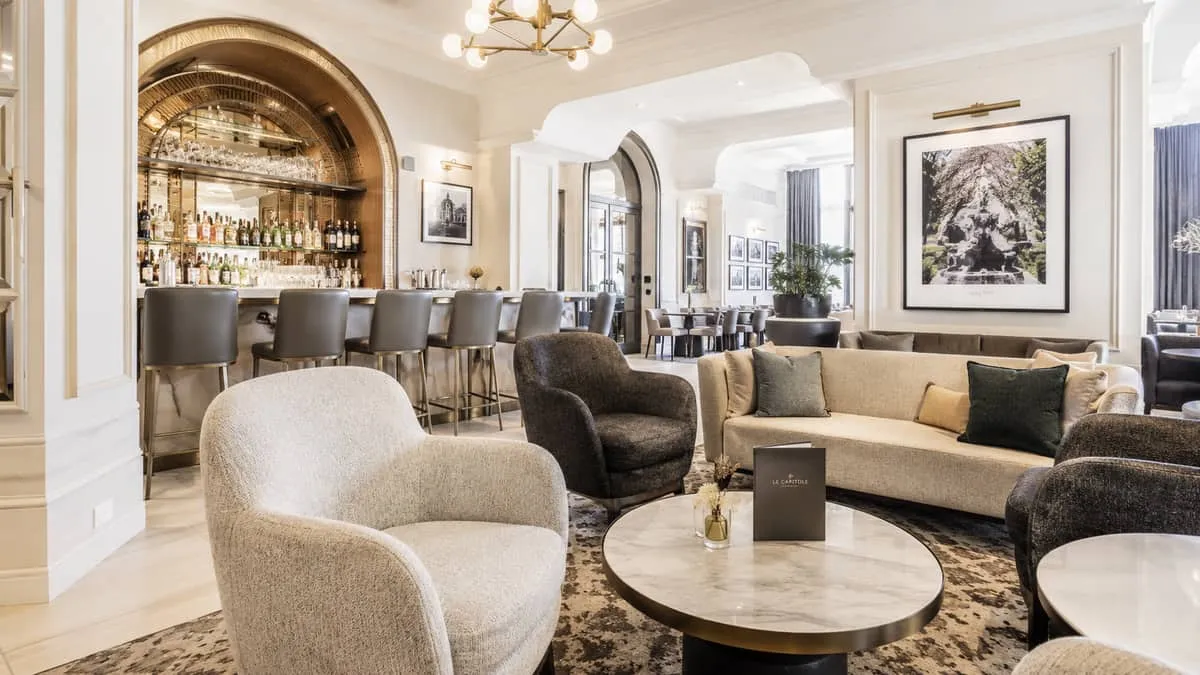 upholstered lounge chairs and a low cocktail table in a warm-toned hotel bar interior, showing the kind of refined loung
