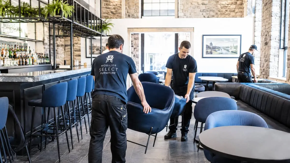 a furniture delivery or installation scenario in a Quebec City bar or lounge space, showing pieces being arranged in a h