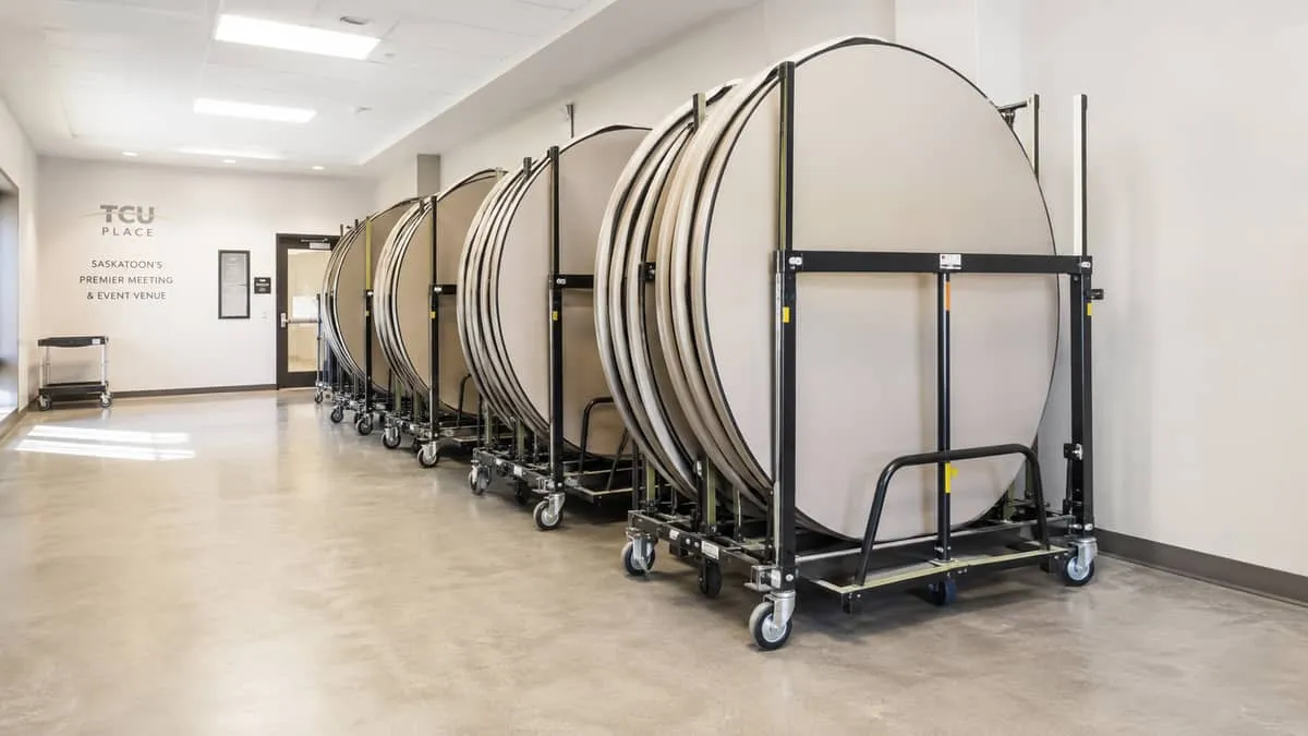 folding banquet tables stored vertically on a table transport cart in a venue storage room, showing organized compact st