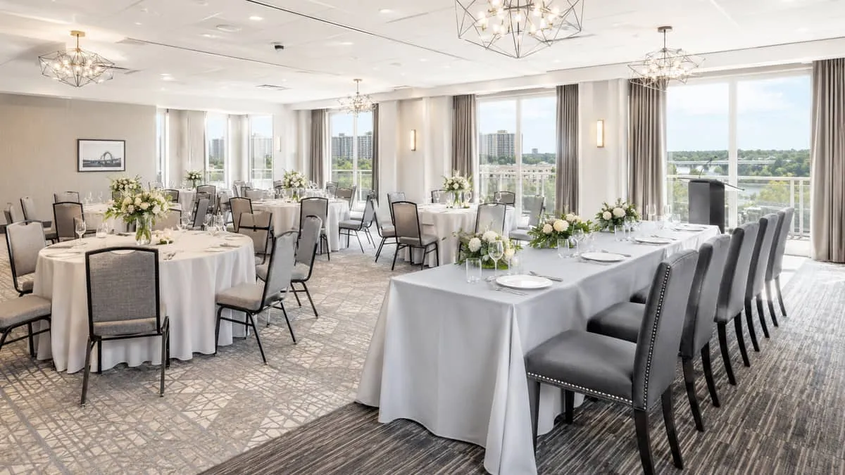 mixed event room setup in a Saskatoon-style venue showing round tables with linens and banquet chairs alongside a head t