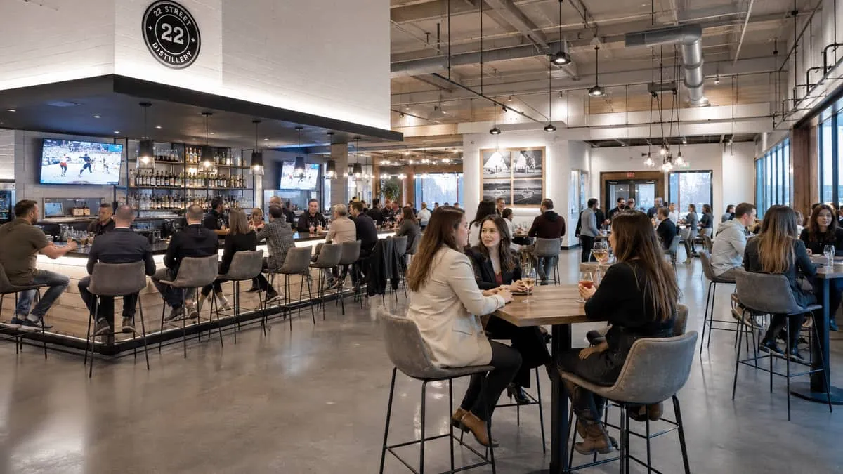 a busy Saskatoon bar or lounge interior during evening service, showing commercial barstools and high-top tables in acti
