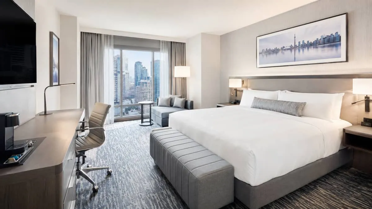 interior shot of a Toronto hotel guestroom or suite with clearly contract-grade furnishings, a headboard wall, upholster