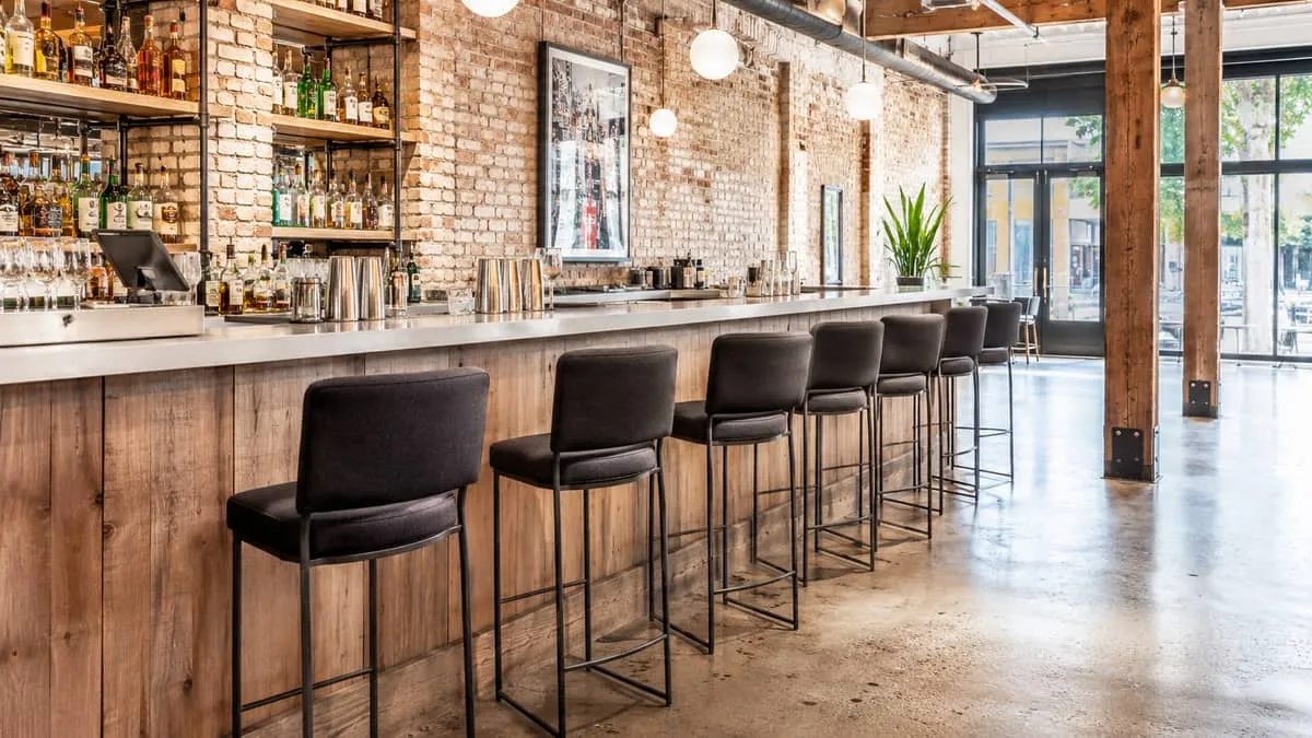commercial barstools at a high bar counter in a Gastown-style exposed brick and wood interior, showing metal frame const