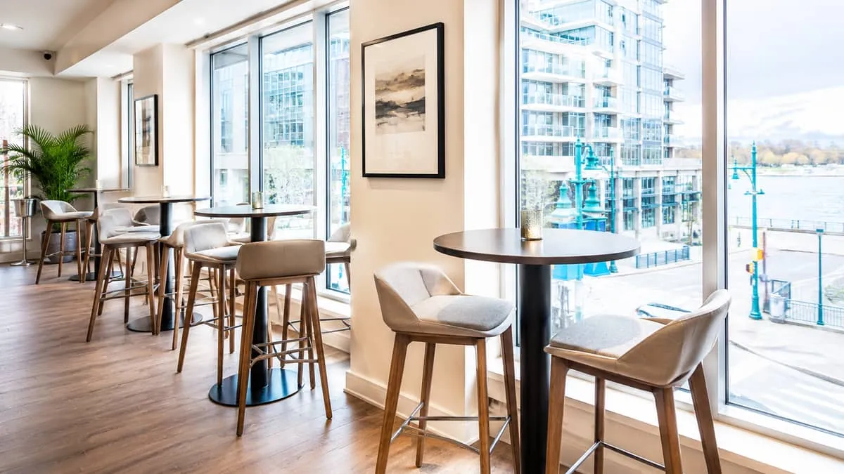 high-top bar tables with commercial barstools arranged along a window in a Vancouver bar or lounge, showing a social sea