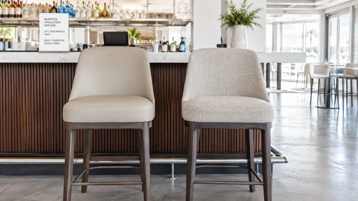 side-by-side comparison of two barstool upholstery options, one in a matte performance vinyl and one in a woven commerci