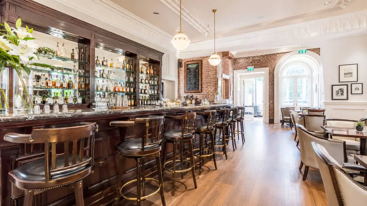 heritage hotel bar interior in Victoria BC showing classic dark wood bar stools with leather seats alongside period-appr