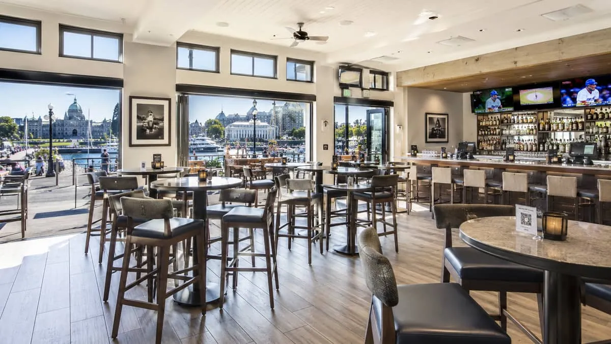 high-top tables with bar stools in a busy waterfront bar in Victoria BC, showing the tables arranged for social seating 
