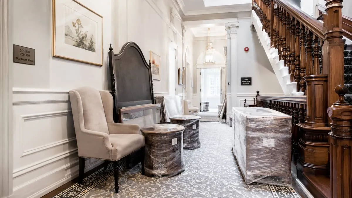 interior shot of a heritage hotel hallway in Victoria with period trim work, showing furniture being moved through a nar