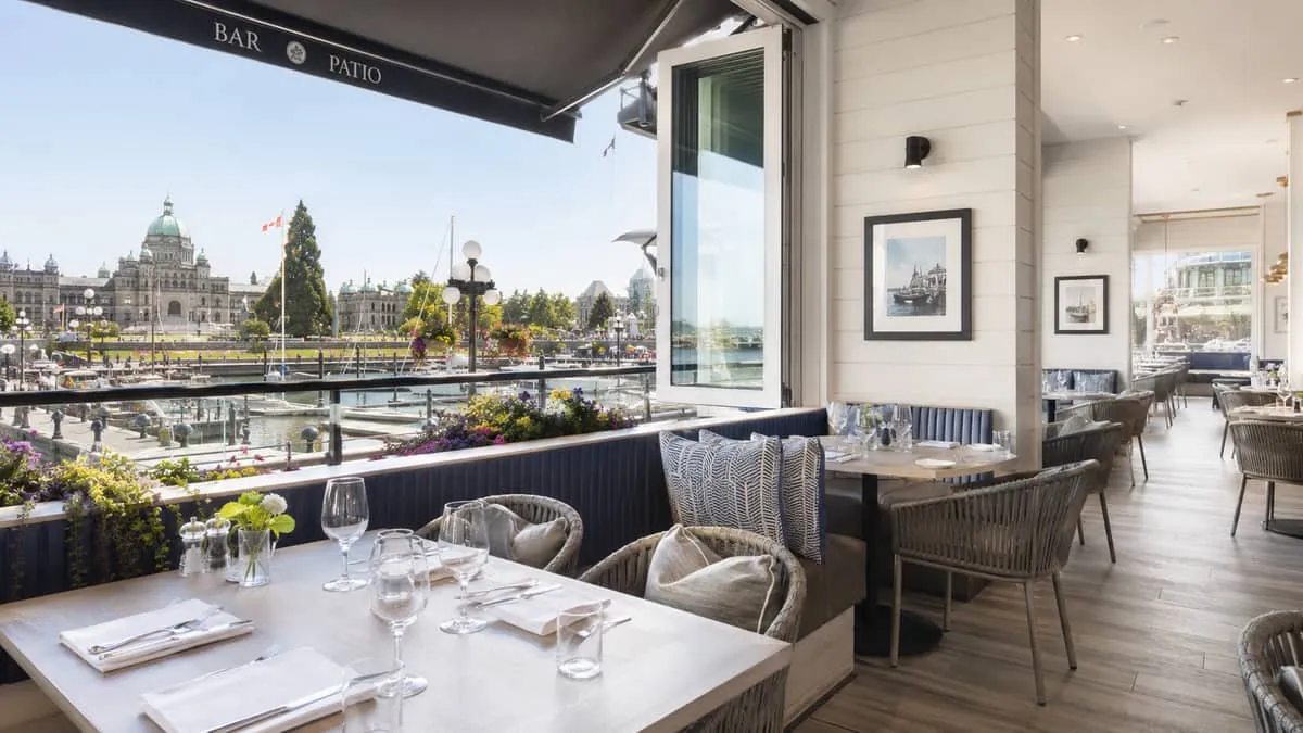 a furnished waterfront restaurant patio or dining room in Victoria BC near the Inner Harbour, showing well-coordinated c