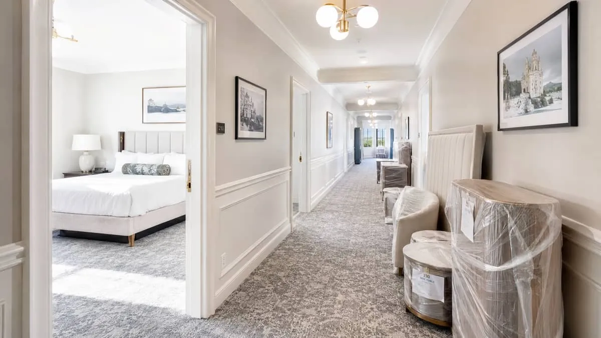 hotel corridor showing one side of the hallway with fresh new furniture staged outside rooms ready for installation, whi