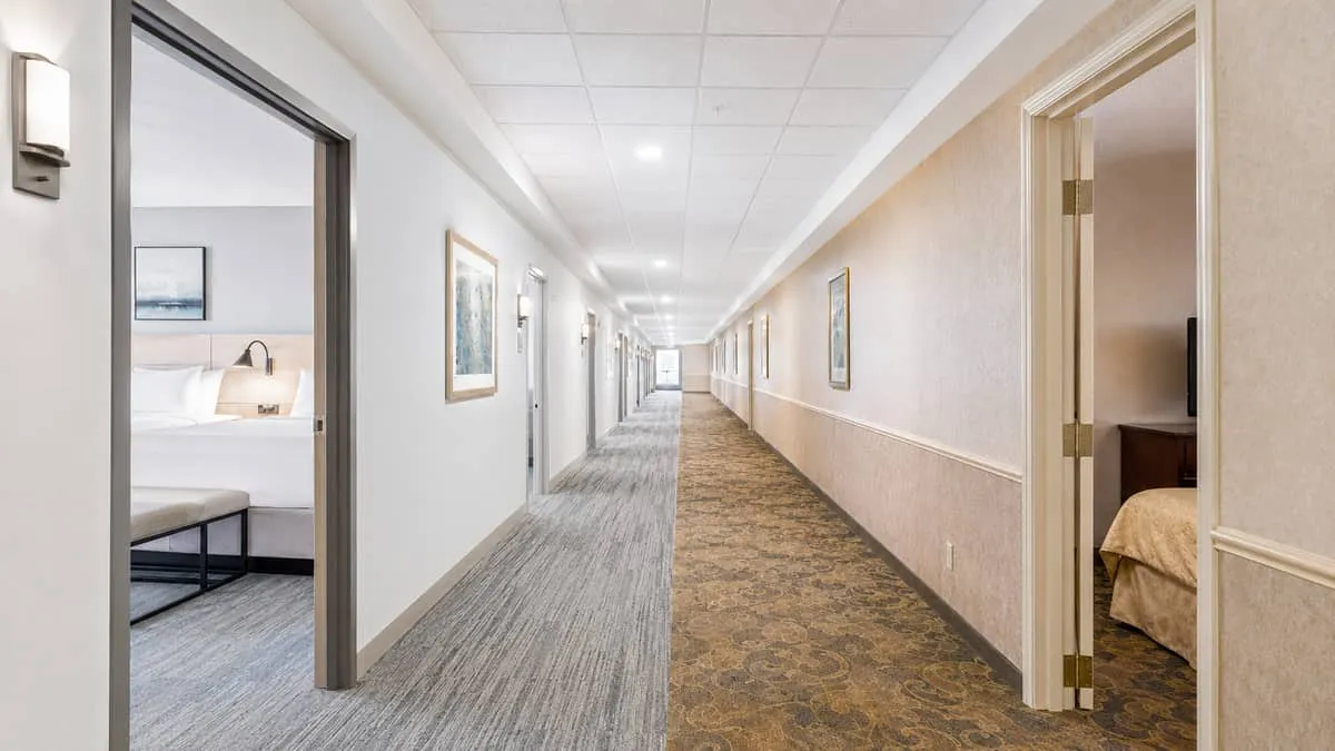 hotel corridor showing one half of the hallway with newly renovated rooms and fresh furniture visible through open doors