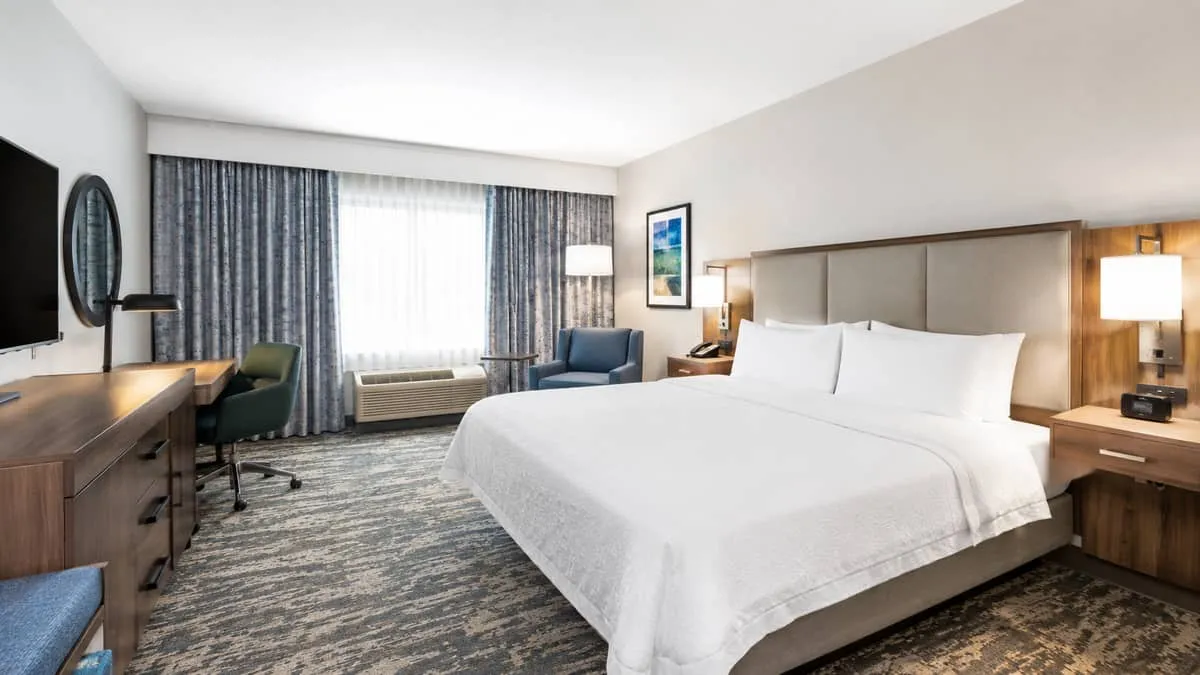 hotel room interior with complete FF&E setup including bed with upholstered headboard, matching nightstands, desk and ch