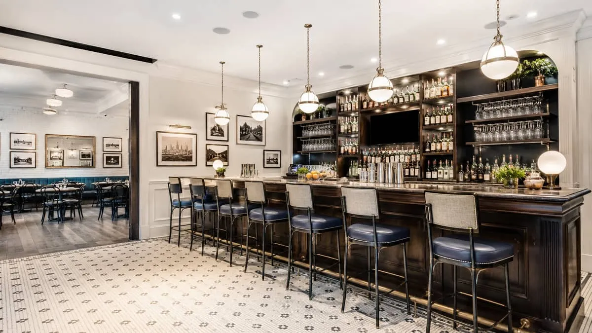 a restaurant bar area with commercial barstools in a mix of metal frame and upholstered seats at a dark wood bar counter
