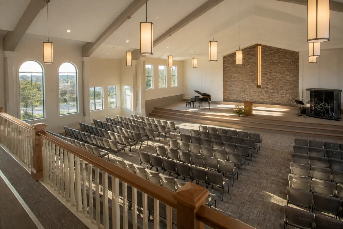 Sanctuary viewed from the balcony with rows of upholstered church chairs below, warm afternoon light