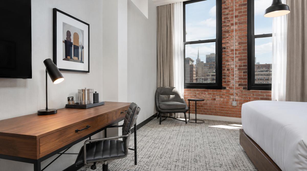 Little Rock boutique hotel guestroom near the Capitol showing cohesive design palette with matching frame finishes and tonal upholstery